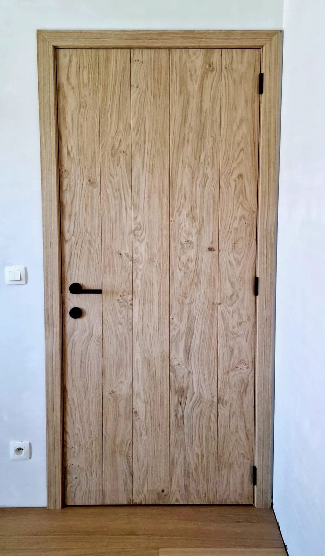 Detail van een eiken plankdeur met zwart beslag