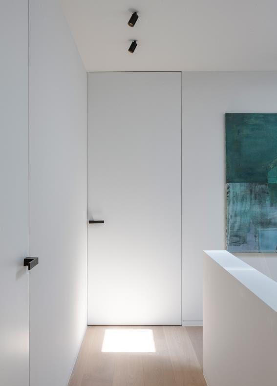 Witte Xinnix invisible deur met zwarte klink in een strakke hal