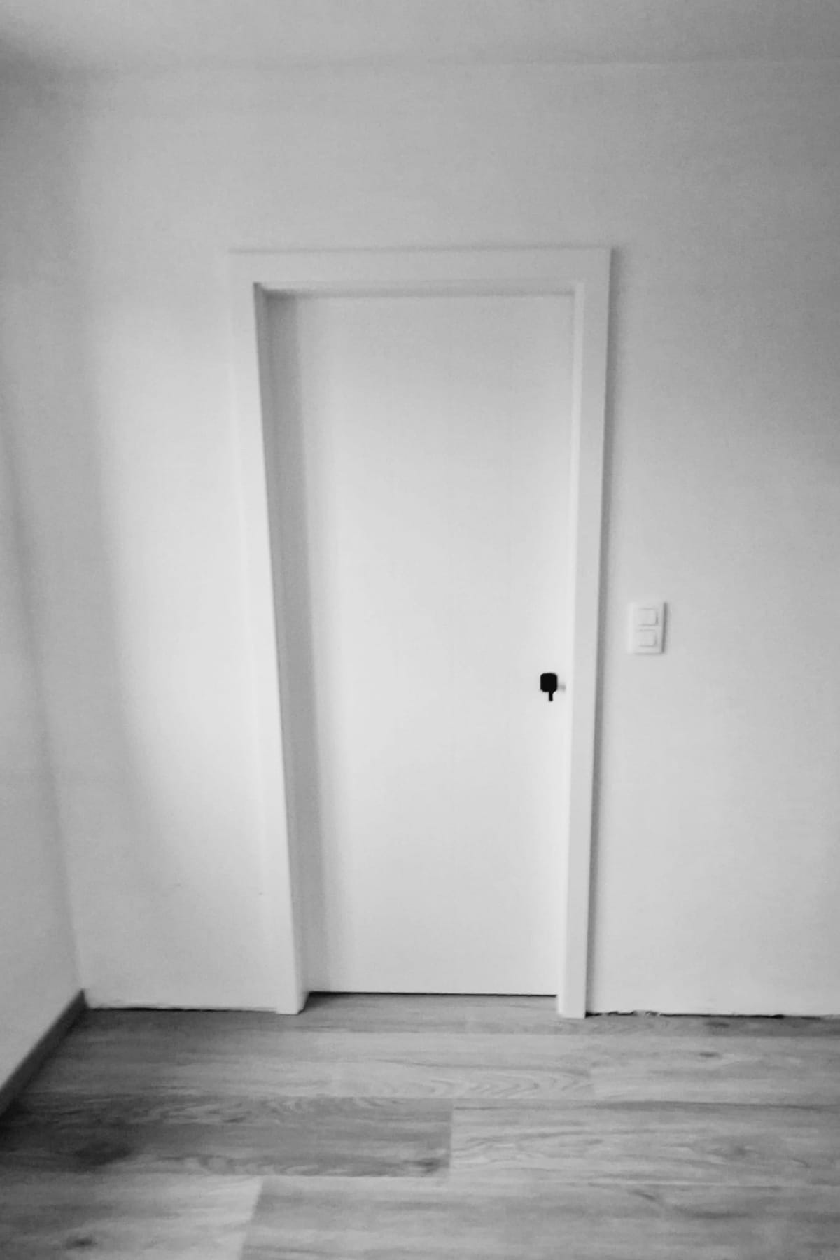 Vlakke witte superlak deur in een witte muur